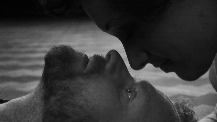 Film still from A Different Kind of Conversation by Kimberley Harvey. Black and white image of two people looking intensely into each other's eyes.