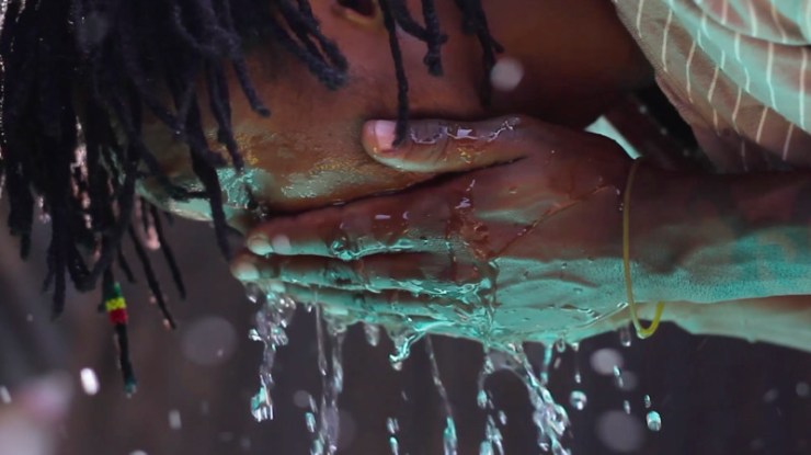 Film still from WHITE CANE by Bo Lee. Close up of a black man washing his face.