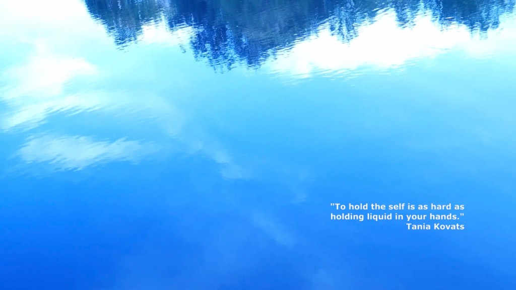 Blue sky reflected in a puddle. 
In the bottom right quarter of the image is a quote by Tania Kovats: "To hold the self is as hard as holding liquid in your hands."